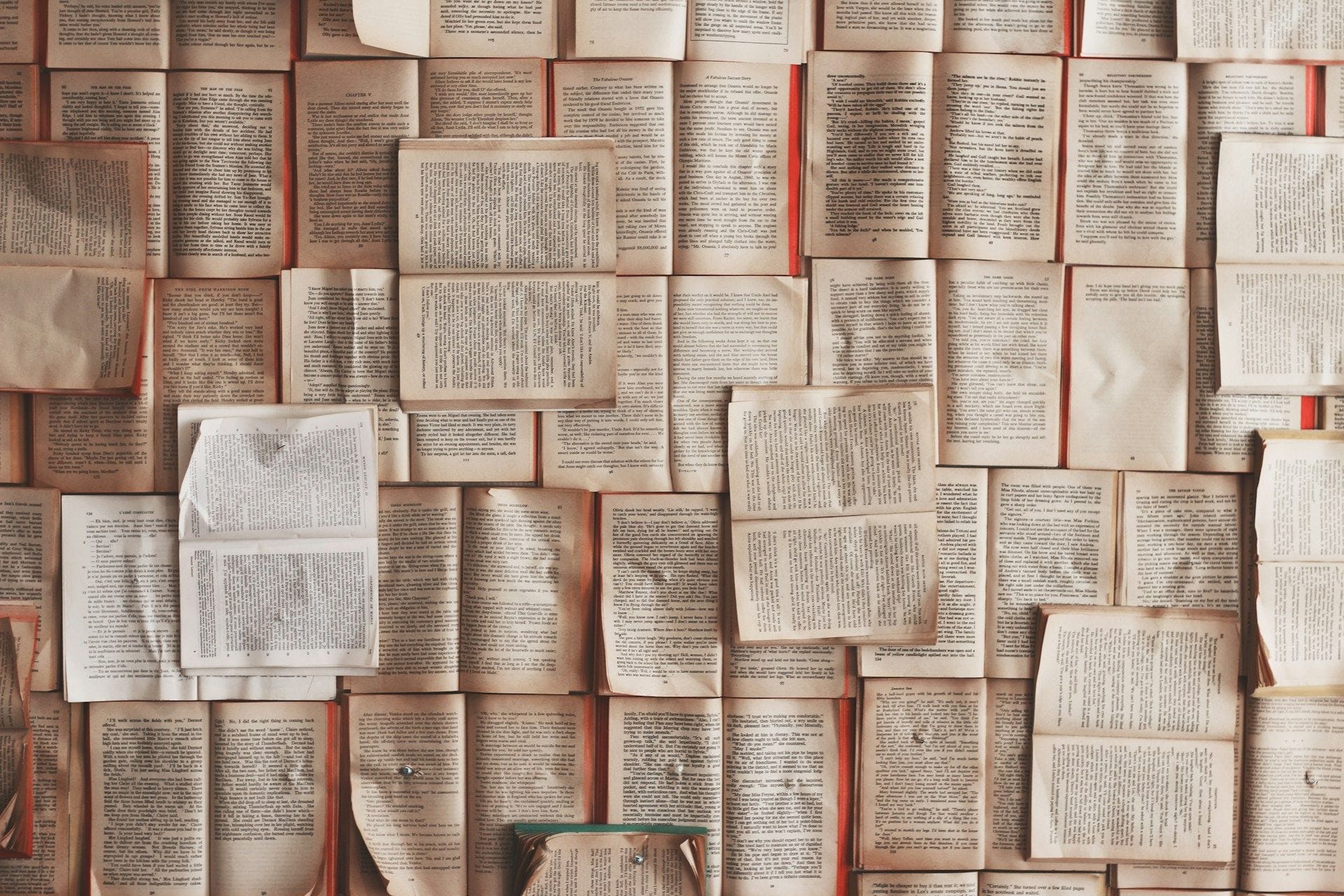 Dotzenes de llibres oberts amb les pàgines cap amunt, disposats en mosaic cobrint tota la superfície