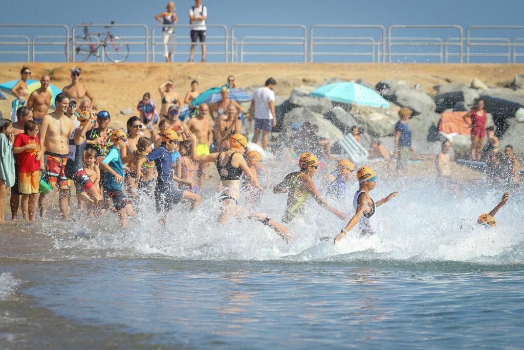 Dotzenes de participants es llancen a la mar des de la platja simultàniament en l'inici d'una prova de natació en aigües obertes