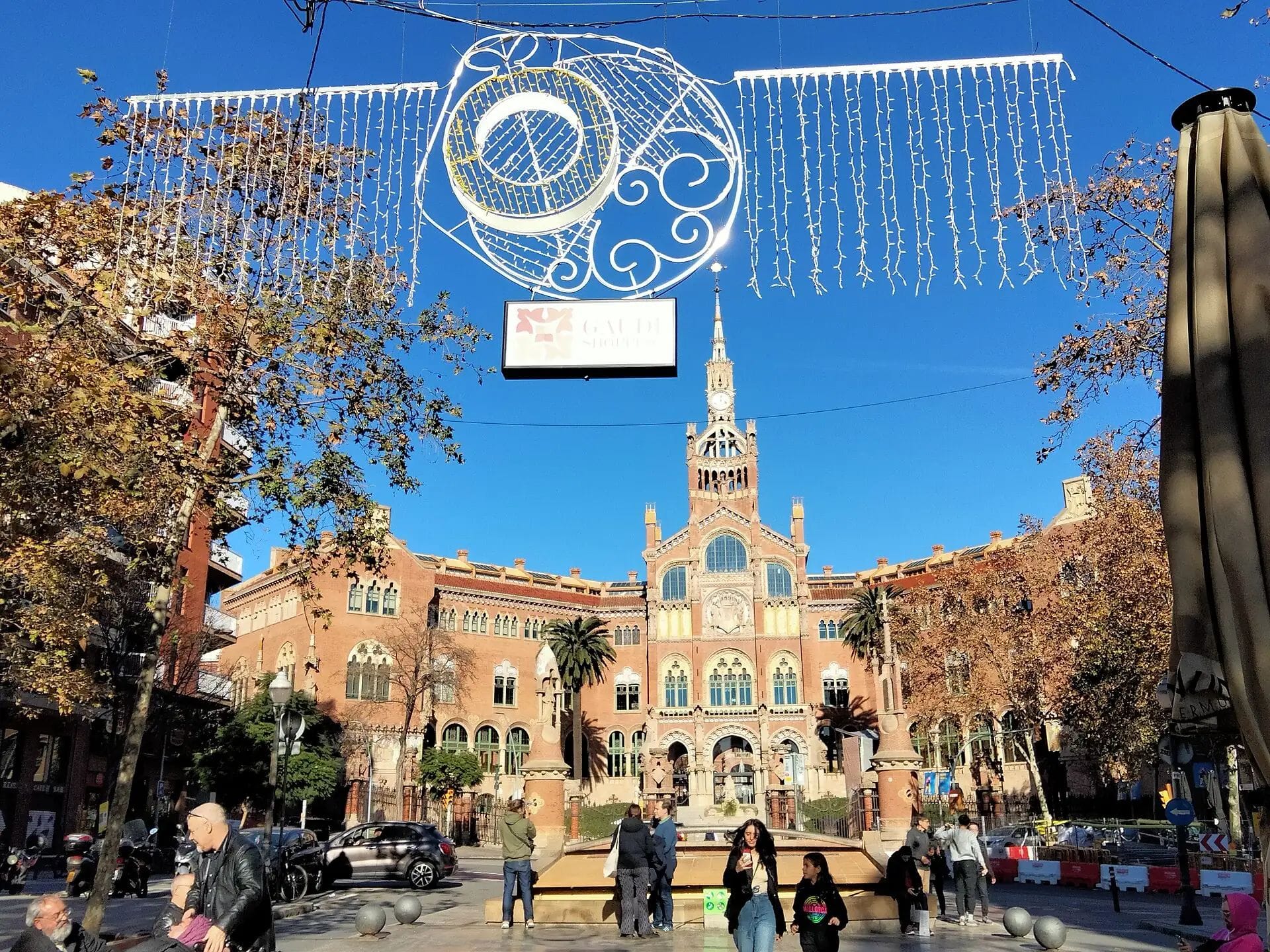 Avinguda amb arbres nus i llums decoratius penjants davant d'un gran edifici modernista amb torre