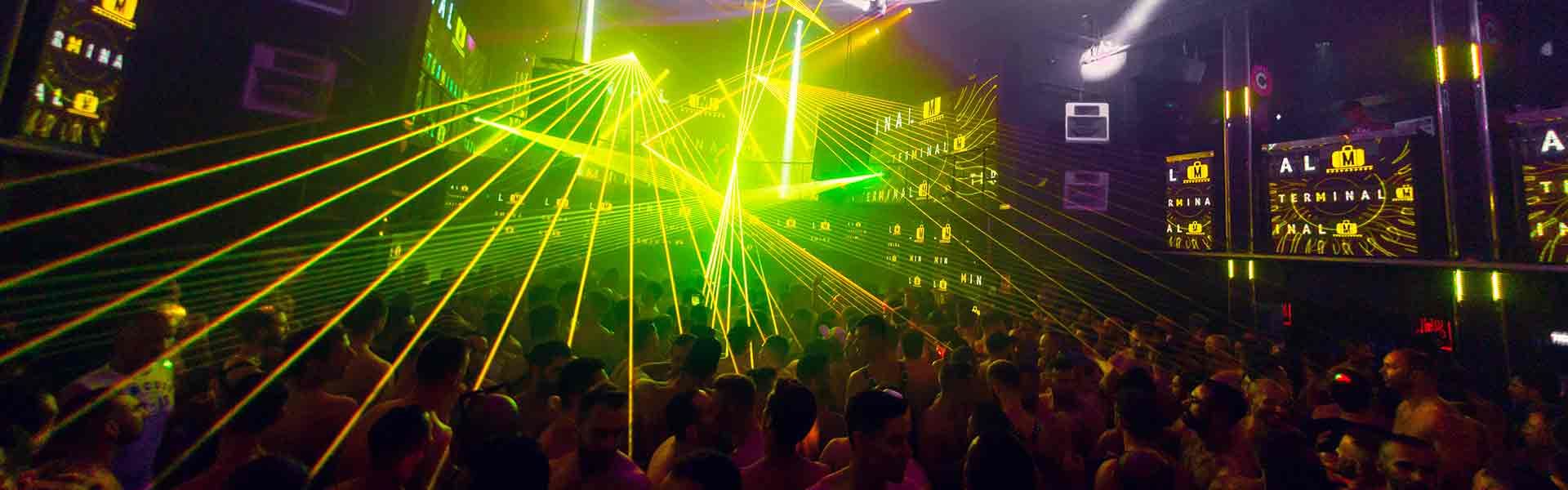 Interior d'una discoteca plena de gent ballant sota feixos de làsers verds que travessen el fum