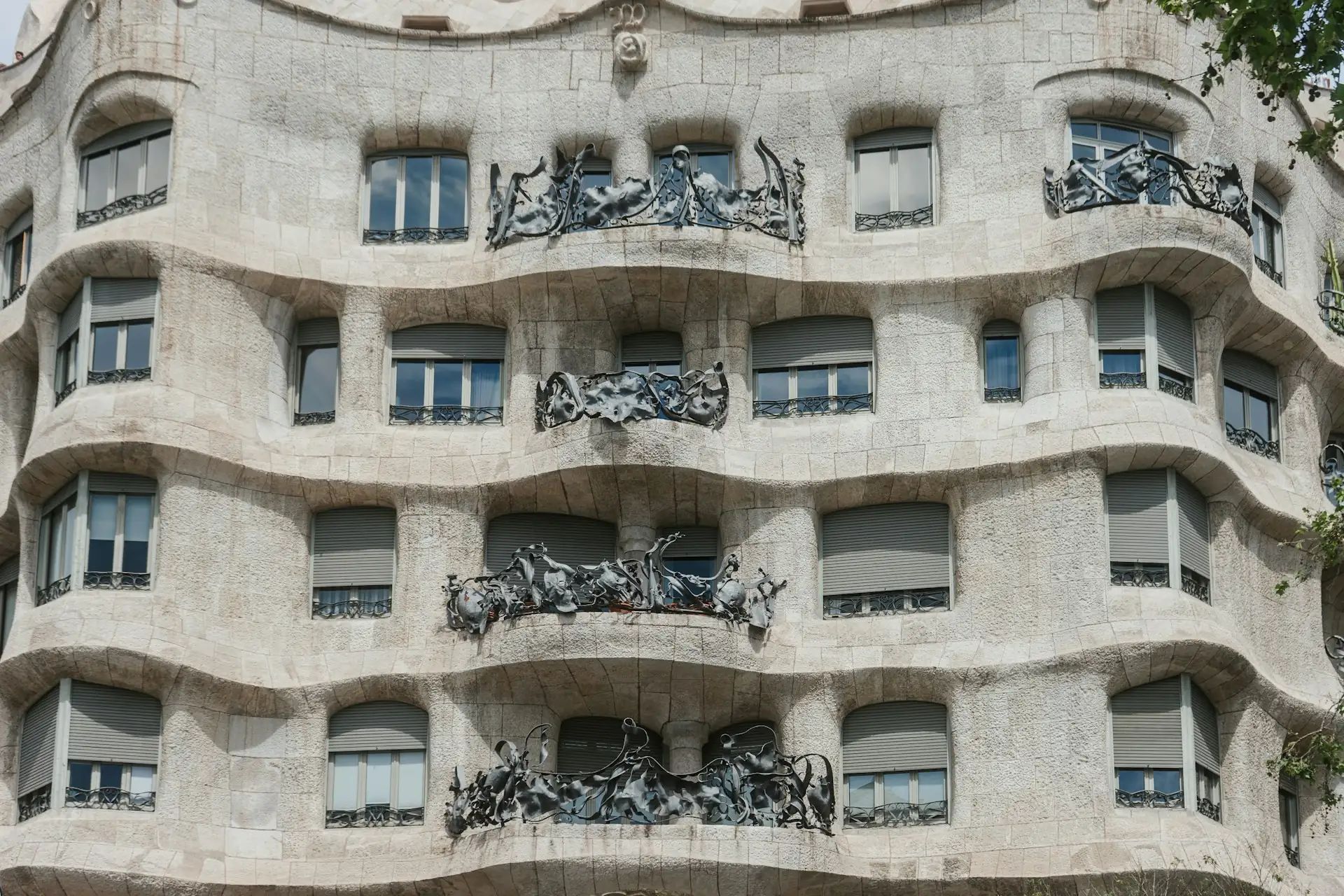 Façana ondulada d'un edifici modernista amb balcons de ferro forjat en forma de plantes marines i pedra esculpida en corbes orgàniques.