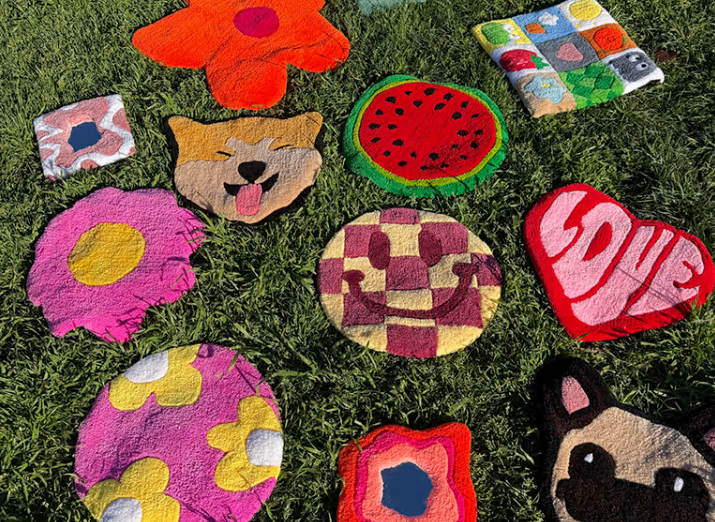 Diverses catifes de tufting de colors esteses sobre la gespa, amb dissenys com una flor, una síndria i un cor