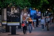 Varias personas pasean junto a la muestra de fotografía de EFE sobre las visitas del Papa instalada en el paseo de Recoletos, a 25 de mayo de 2026.
