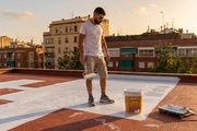 Un trabajador usa una pintura reflectante que potencialmente reducirá las temperaturas dentro del edificio
