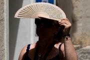  En la imagen, una persona con un abanico se protege del sol