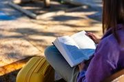 Niña sentada en un banco leyendo un libro