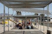 Varias personas intentan protegerse del sol bajo una pérgola de la zona del Fòrum de Barcelona durante la ola de calor